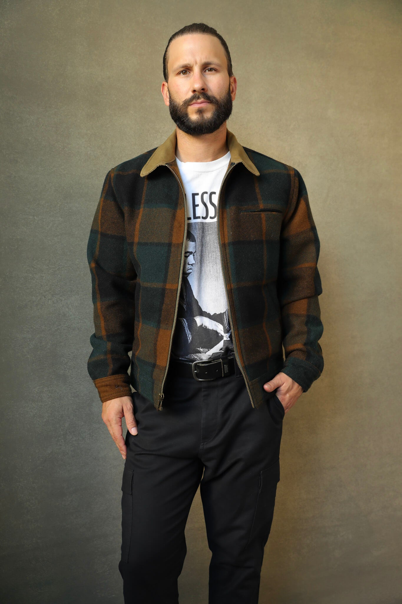 A man wearing a two-tone designer menswear jacket with a chest pocket and welt hand pockets. The jacket is made of wool and has a full-zip closure.