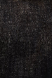 A close-up texture shot of dark indigo denim fabric, showing the detailed weave and subtle fading.