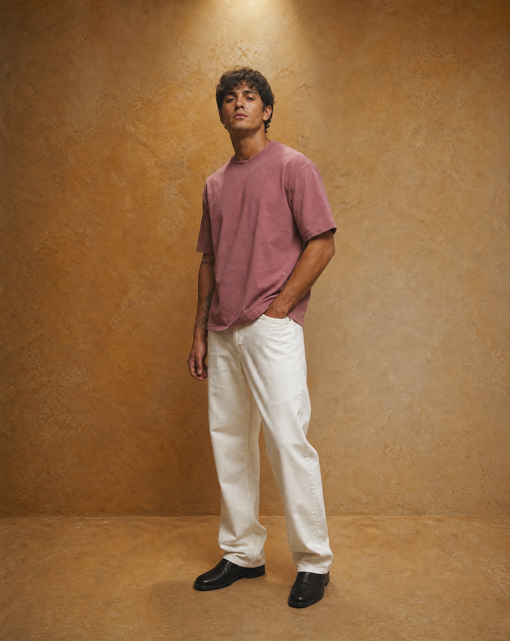Generated_with_Kive.ai_-_Create_an_additional_studio_product_photo_of_the_same_male_model_wearing_the_same_plain_pink_cotton_t-shirt_and_white_pants__keeping_the_same_warm_textured_ta.png