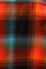 A close-up of a plaid fabric pattern with prominent red, orange, black, and teal stripes.