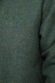 Close-up of a textured knit fabric in a heathered teal-green color, showing the weave and a folded seam on the right side.